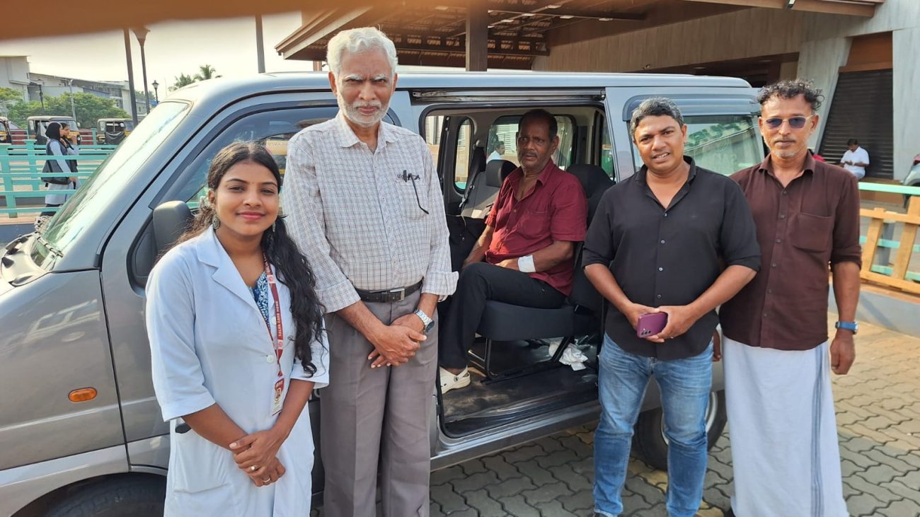 A close-up photograph of 73-year-old Mohanan looking weary but relieved, sitting at the Kuttippuram railway station while local social workers and Selva Care coordinators stand supportively beside him during his rescue.