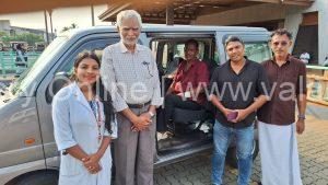A close-up photograph of 73-year-old Mohanan looking weary but relieved, sitting at the Kuttippuram railway station while local social workers and Selva Care coordinators stand supportively beside him during his rescue.